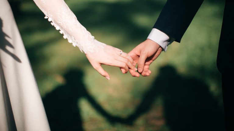 結婚式で手を繋ぐ男女と影